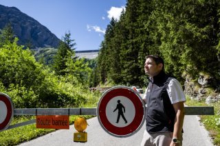 Gregory Logean, président de la commune d'Hérémence devant la barrière qui ferme la route, suite à l'éboulement de roches proche du barrage de la Grande Dixence jeudi 17 juillet. KEYSTONE/JEAN-CHRISTOPHE BOTT